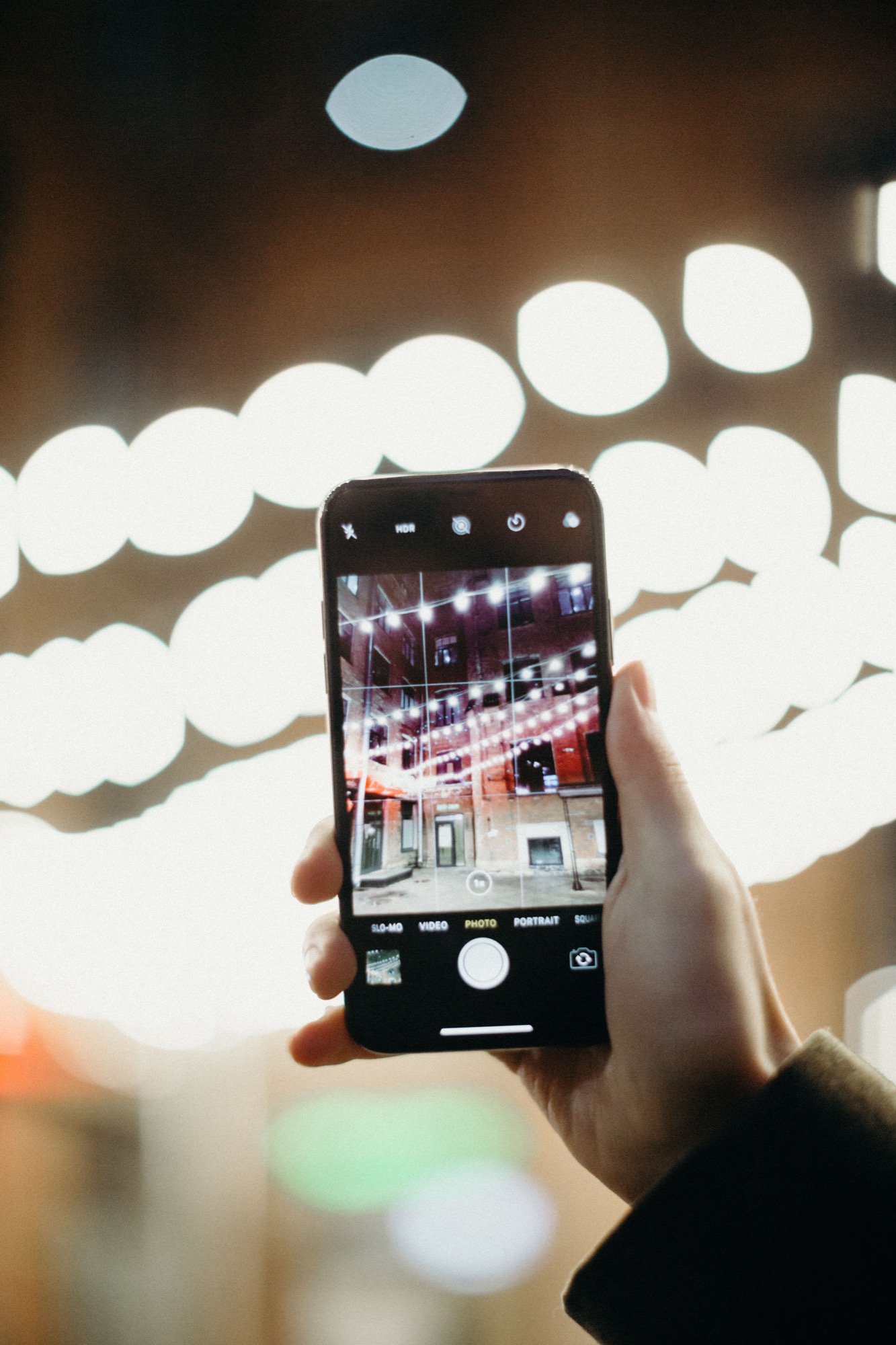 Smartphone mit Stadtlichtern als Munich Now App-Hero